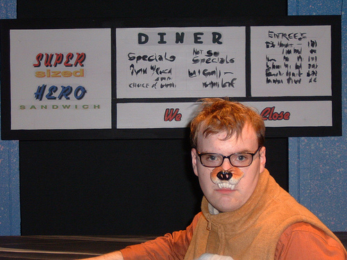 Man looking at camera wearing an animal nose prop with a set in the background