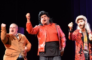 3 actors on stage with their fists raised in the air