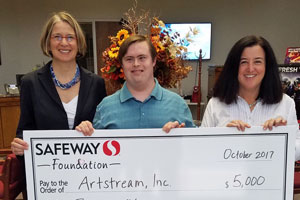3 individuals, 2 women and 1 man, are holding up a check, while smiling.