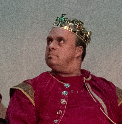 A man in a kings crown and robe looking off to the left.
